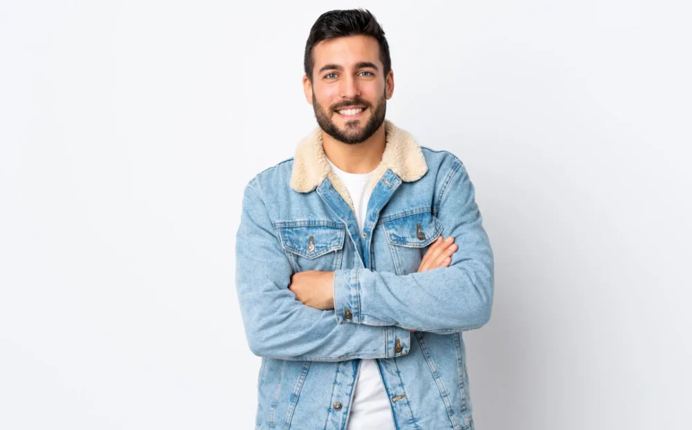 Young handsome man with beard isolated on white background keeping the arms crossed in frontal position