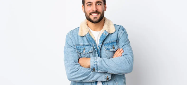 Young handsome man with beard isolated on white background keeping the arms crossed in frontal position