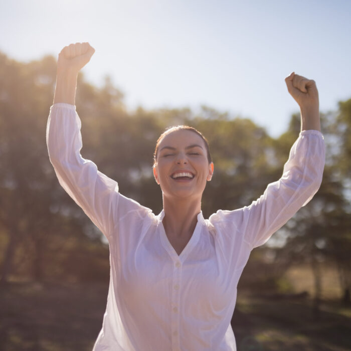 Happy woman standing with arms up during safari vacation