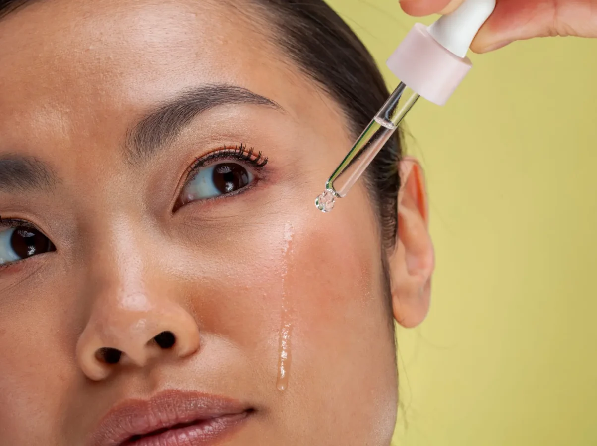 Close-up of woman applying serum on face